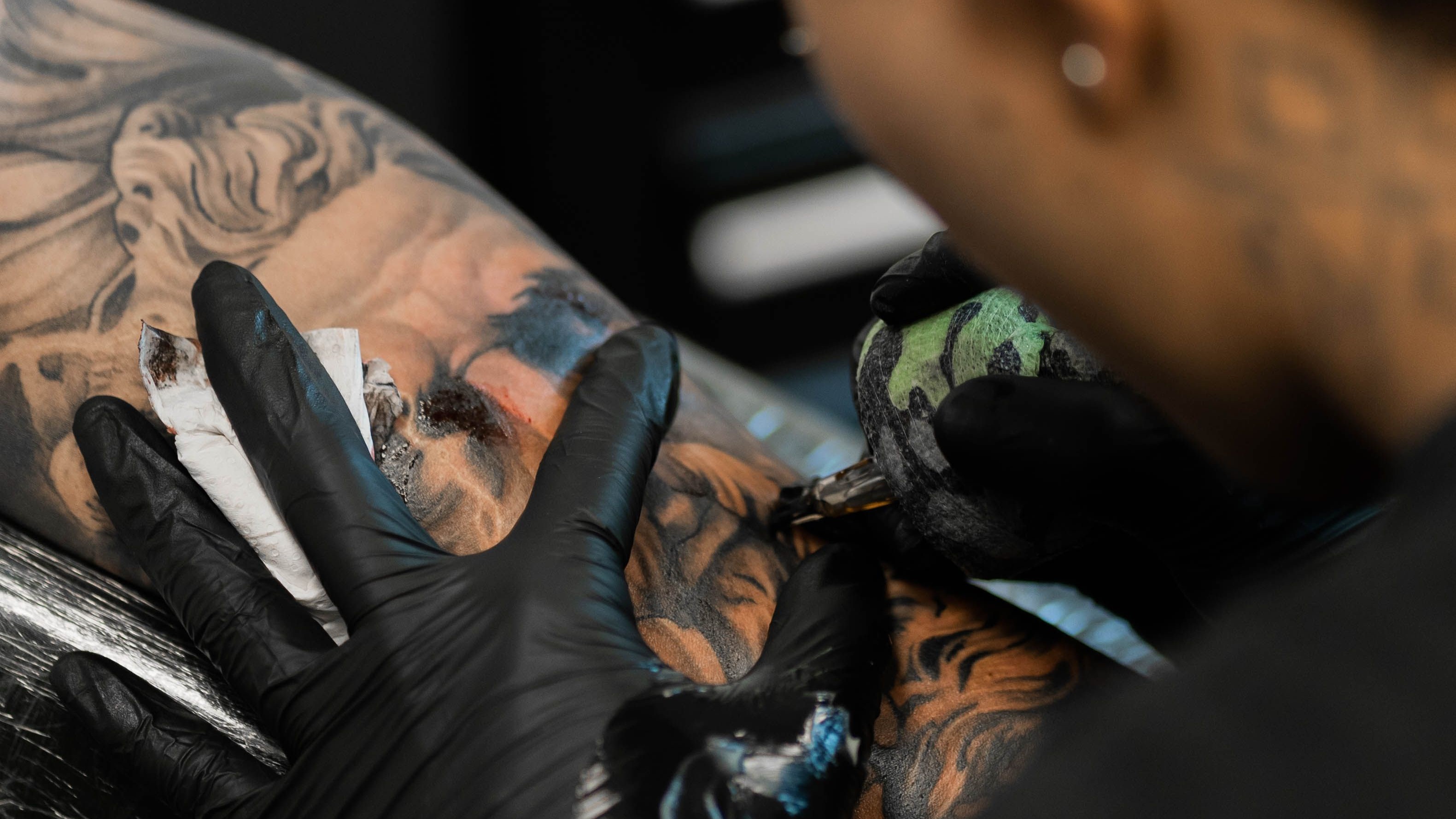 Tatuador em sessão de retoque em sleeve de realismo